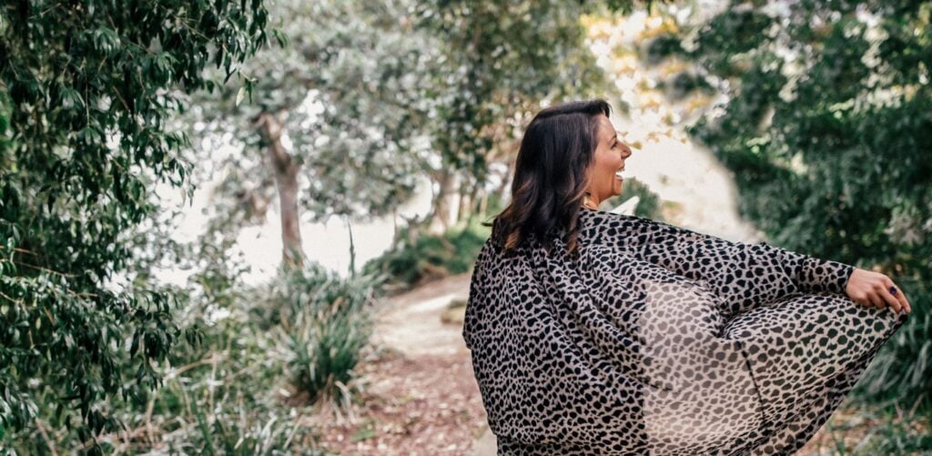 woman with her back to the camera and her arm out smiling and laughing outside