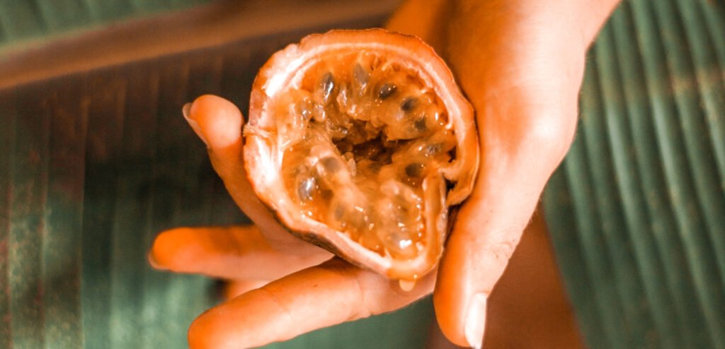 hand holding half a passionfruit. Imagery of female genitals showing masturbating