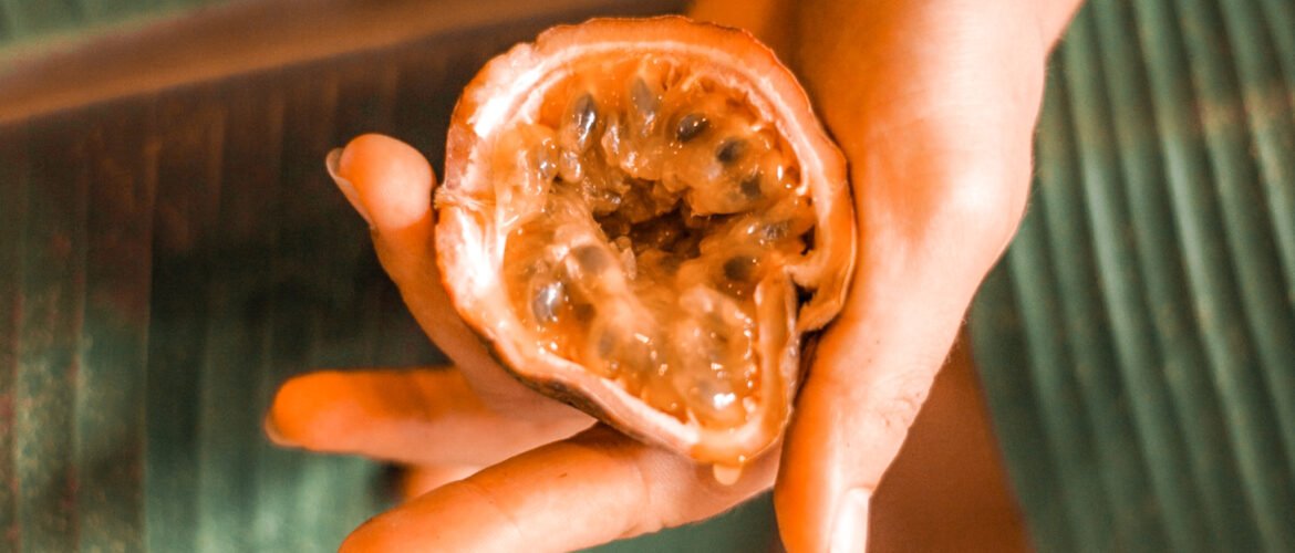 hand holding half a passionfruit. Imagery of female genitals showing masturbating