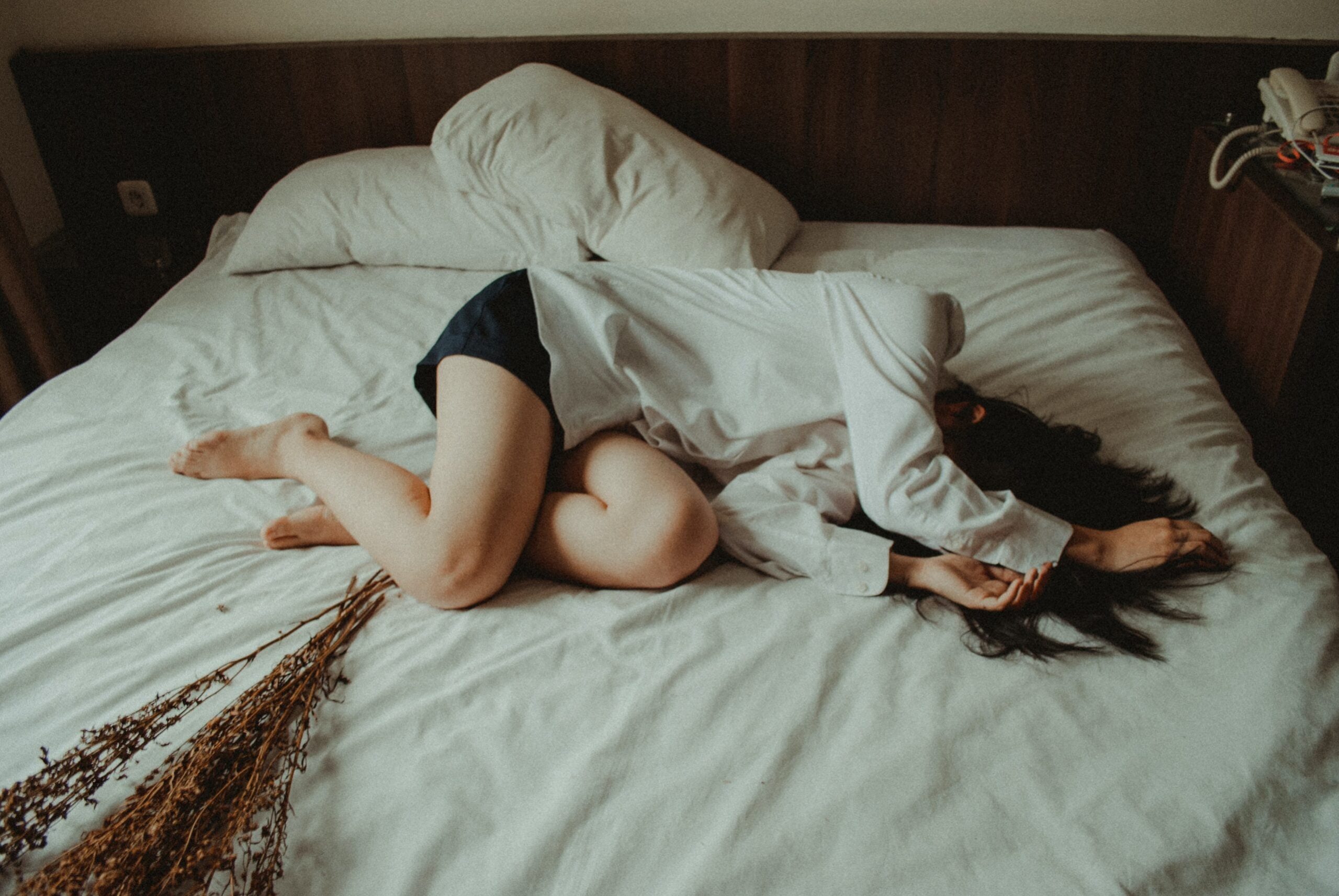 woman lying on her side on bed covering her face wishing for more connection and intimacy after sex