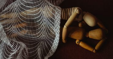 figurines lying down hugging each other under net blanket demonstrating a position after sex after birth