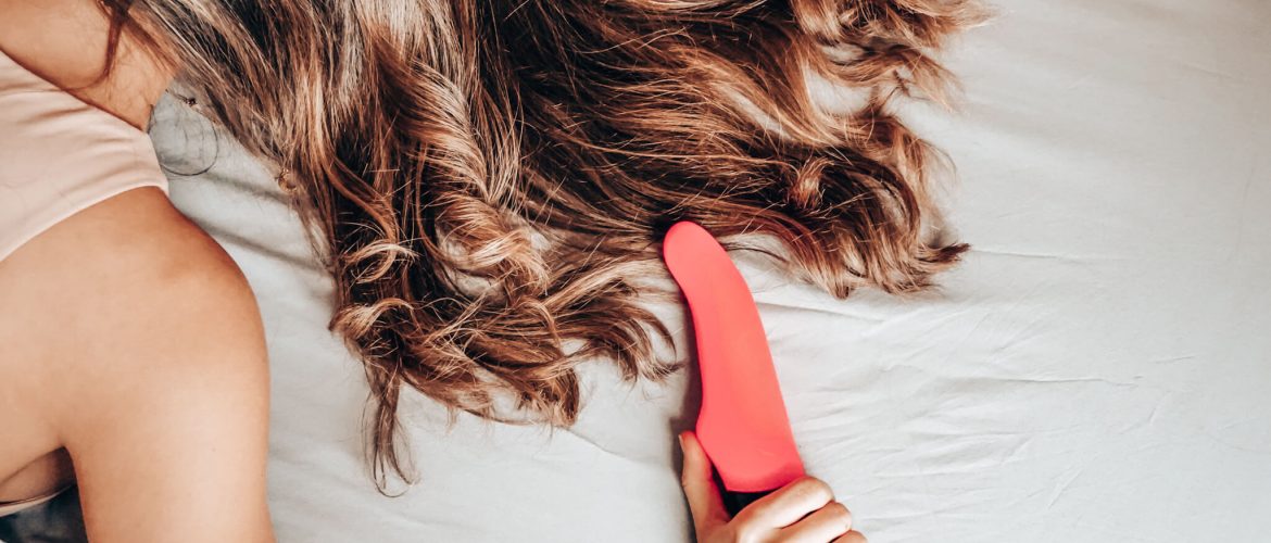 woman lying face down on the bed with a vibrator after masturbation. her hair is covering her face