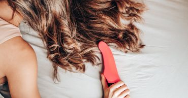 woman lying face down on the bed with a vibrator after masturbation. her hair is covering her face