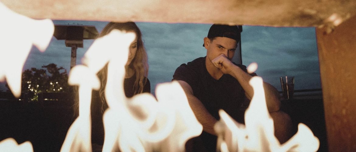 couple looking at fire, couple contemplating relationship problems, woman sitting next to man, couple