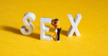 word sex in block letters with man and woman dolls hugging and kissing.